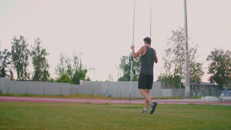 A-javelin-Thrower-walks-around-the-stadium-with-spears-and-collects-them.-Go-with-a-spear-in-hand-against-the-background-of-the-stadium-stands.-The-training-of-the-Olympic-champion.